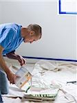 man pouring paint into a roller tray