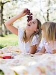 two girls in a blossoming orchard eating grapes