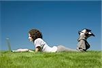 woman lying on the grass using a laptop