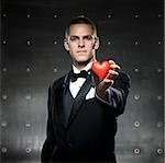 man in a tuxedo holding a heart