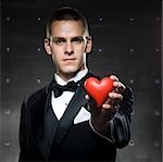 man in a tuxedo holding a heart