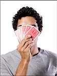 man covering his face with playing cards