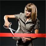 businesswoman cutting a red ribbon