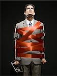 businessman wrapped up with red tape