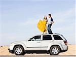 couple sur le toit de leur voiture sur le bord de la route