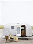 Airstream remorque classique avec un tableau mis en place en face de lui sur le sable