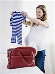 pregnant woman holding up baby clothing