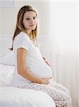 pregnant woman sitting on a bed