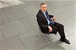 Businessman sitting on office chair in lobby, Munich, Bavaria, Germany