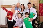 Grands-parents, parents et enfants tenant des cadeaux de Noël
