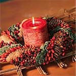 Red candle in wreath with fir cones