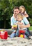 Father playing with two children in sandbox