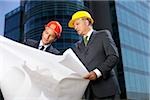Two Businessman with hardhats watching a plan