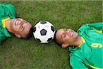 Two Brazilian soccer players lying on grass