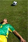 Exhausted Brazilian soccer player lying on grass