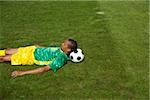 Exhausted Brazilian soccer playing lying on grass