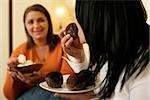 Two women eating meringues and muffins together, selective focus