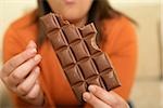 Woman with brown hair holding a chocolate bar in her hand, selective focus