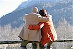 Mature couple sitting on a fence and embracing