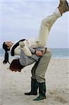 Longhaired Man pulling his Girlfriend onto his Back - Fun - Physicalness - Relationship - Beach