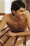 Darkhaired Man lying procumbently on a wooden Bench - Look - Allurement