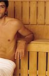 Darkhaired Man resting his Arms on a wooden Bench - Heat - Sauna - Wellness