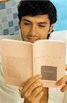 Darkhaired Man in a Bath Robe reading a Book - Wellness - Leisure Time - Print Media