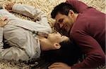 Jeune homme couché tête à tête avec sa petite amie sur un tapis - relation - amour - Accueil - salon