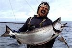 Pêcheur commercial tenant un roi grand saumon capturé sur un ligneur à saumon, golfe de l'Alaska