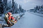 Several mailboxes lined up in a row with one decorated with a Christmas wreath during winter in Alaska