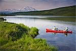 Mature couple canoes on Wonder Lake with Mt. Mckinley in background in Denali National Park, Alaska during Summer