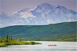 Three people in one canoe on Wonder Lake with Mt. Mckinley in background in Denali National Park, Alaska during Summer