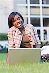 College Student Sitting Outdoors Using a Laptop Computer