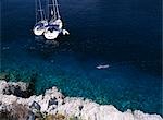 Man snorkelling past two yachts moored in small bay on the island of Bisevo off Vis,Croatia.