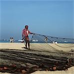 Fisherman pulling nets on the beach,Goa,India.