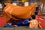 Une femme étant montrée des tissus par un vendeur dans un magasin à Jaipur, Rajasthan, Inde