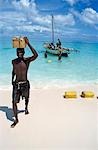 Man carrying box on head on beach,Vamizi Querimbas,Mozambique