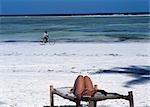 Tourist on sun lounger and cyclist,Matemwe beach,Zanzibar,Tanzania