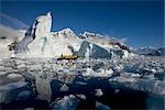 Touristen im Schlauchboot durch Eisberg, Antarktis