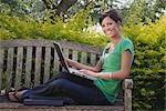 Étudiant à l'Université assis sur un banc à l'aide d'un ordinateur portable