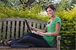 University Student Sitting on a Bench Using a Laptop Computer