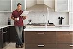 Man reading a newspaper in kitchen