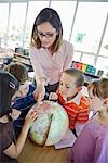 Kinder und Lehrer in Grade One Klassenzimmer Globus betrachten