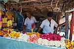 Two men selling flowers and garlands off a stall in the market in a small town in the Western Ghats, Munnar, Kerala, India, Asia
