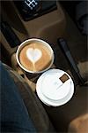 Zwei Kaffees mit Herzen gestalten in Schaum in Auto-Getränkehalter