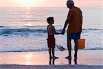 Grandfather and Grandson on the Beach with a Net and Bucket