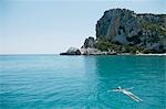 Woman Swimming in blue,rocky bay