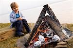 boy looking at potatoes barbecue fire