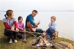 two girls,boy and man roasting sausages