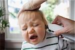 Adult putting thermometer in ear of crying baby